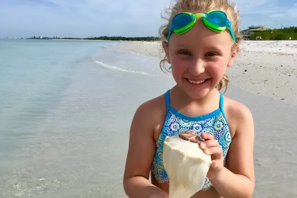 A girl shows off her seashell treasure
