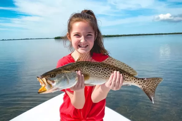 A young girl shows off the fish she caught