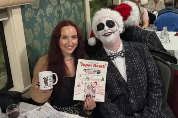 A female teen and character from the Murder Mystery Train smile for the camera