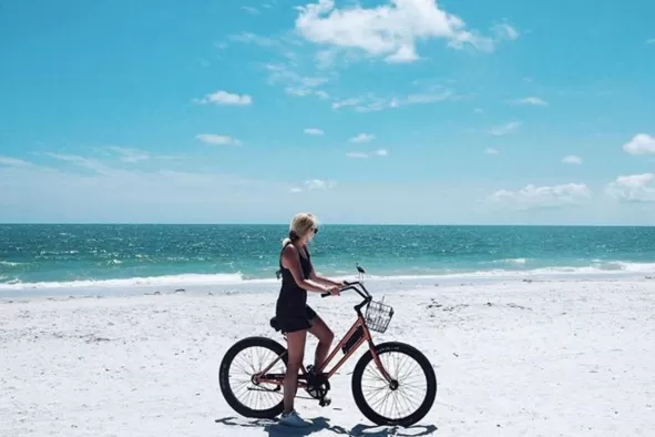 A woman rides a bike along the shoreline
