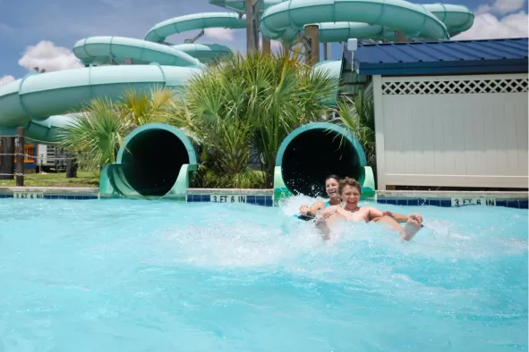 A mom and her son go down the water slide