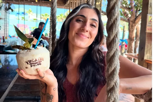 A woman holds up her coconut drink at Yucatan Liquor Stand