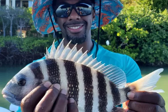 A teenage male holds up his prize catch after a day of fishing