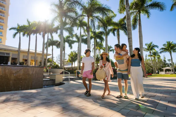 A family walks along the boardwalk outside their resort