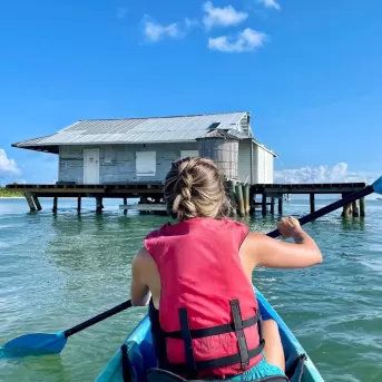 Una mujer con una camisa rosa remando en un kayak azul