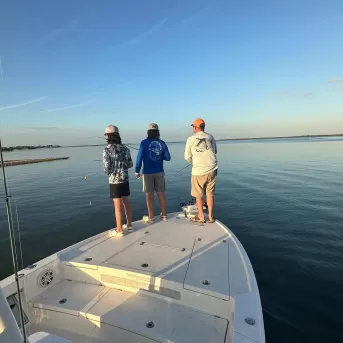 trois personnes pêchant à la proue du bateau