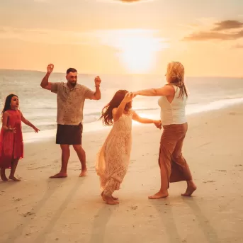 Portrait de famille au coucher du soleil sur la plage dansant