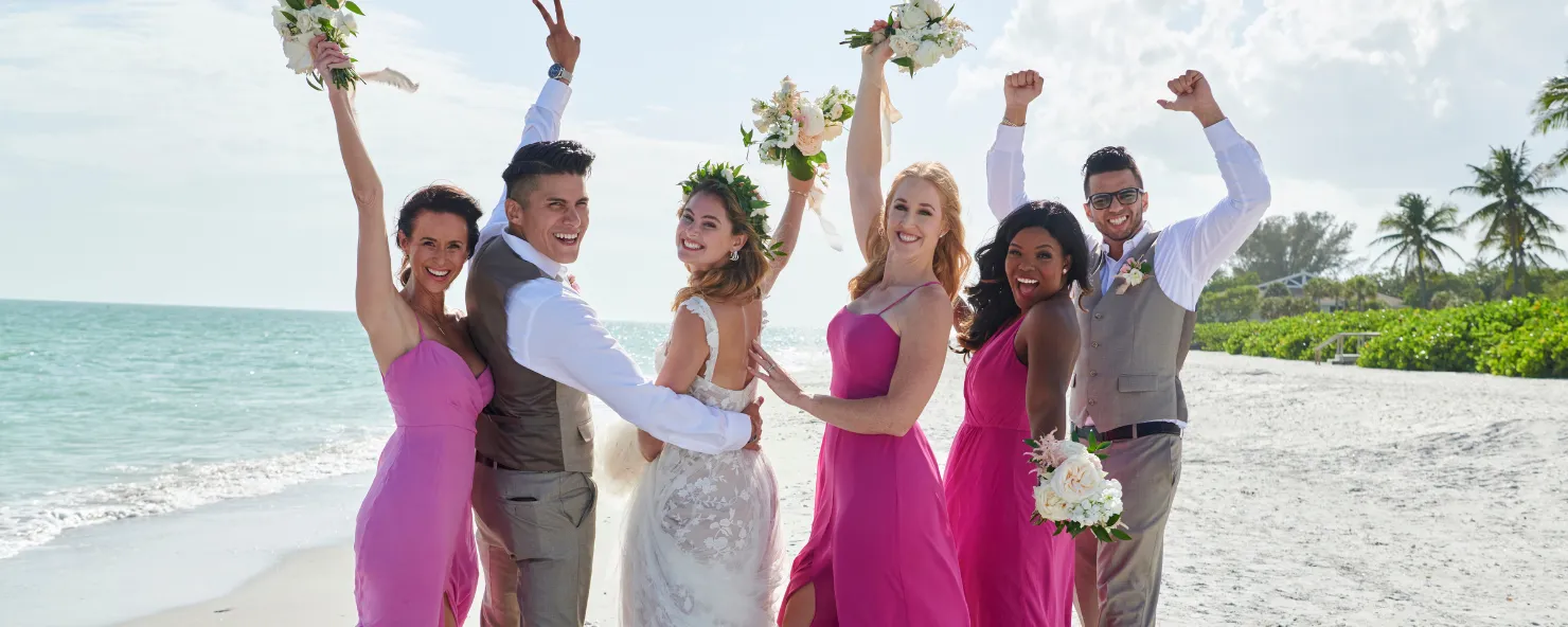 A wedding party celebrates on the beach