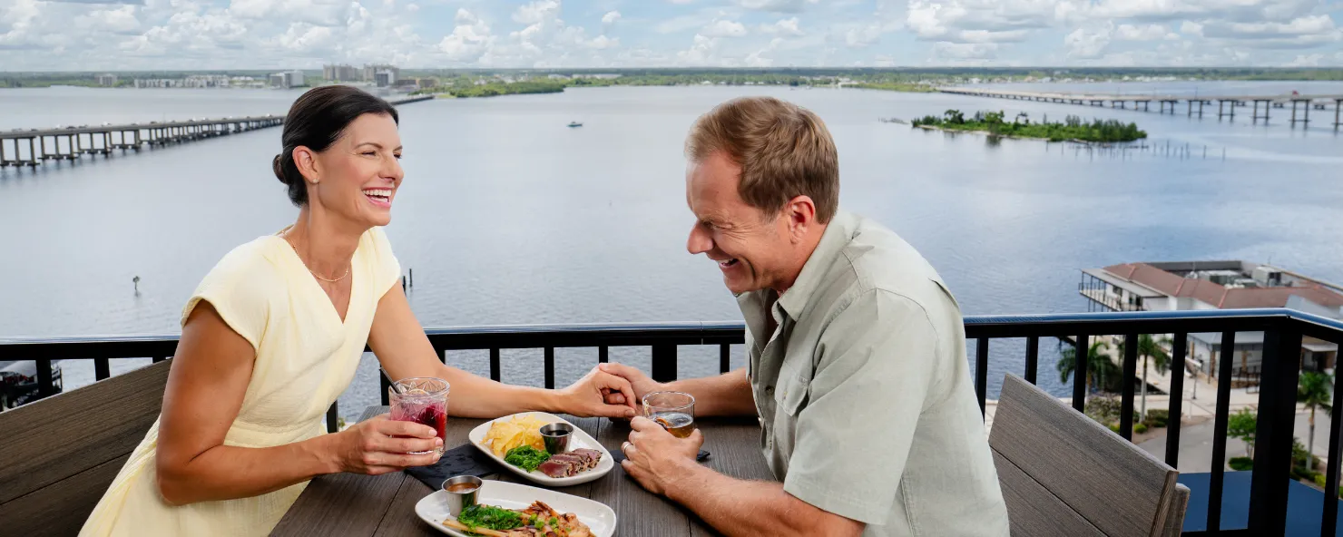 A couple enjoys dining at a rooftop bar overlooking the river
